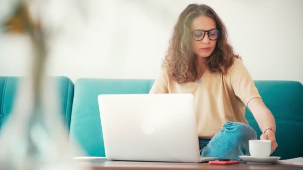 Een jonge vrouw remote werknemer werken vanuit huis met een laptop — Stockvideo