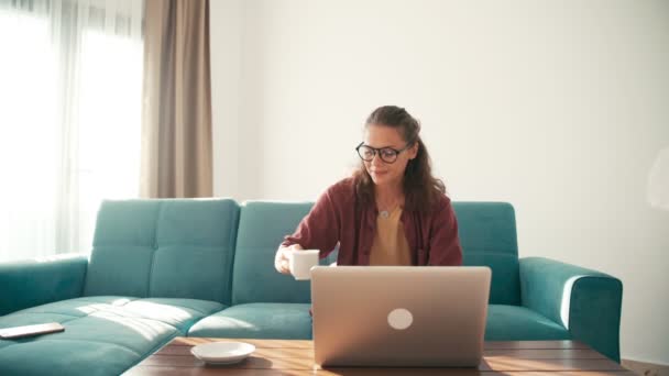 Een jonge vrouw externe werknemer die thuis werkt en een telefoontje beantwoordt. — Stockvideo