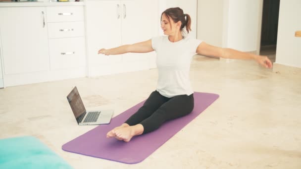 Atractiva joven haciendo yoga estirando yoga en línea en casa. — Vídeo de stock