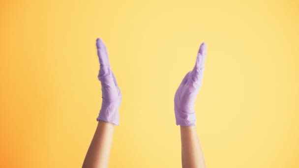 Mulheres mãos em luvas de látex médicos batendo palmas sobre o fundo amarelo brilhante — Vídeo de Stock
