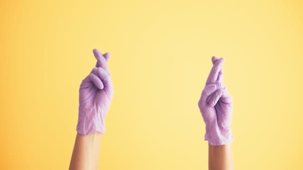 Vrouwen handen in medische beschermende latex handschoenen bidden met gekruiste vingers — Stockvideo