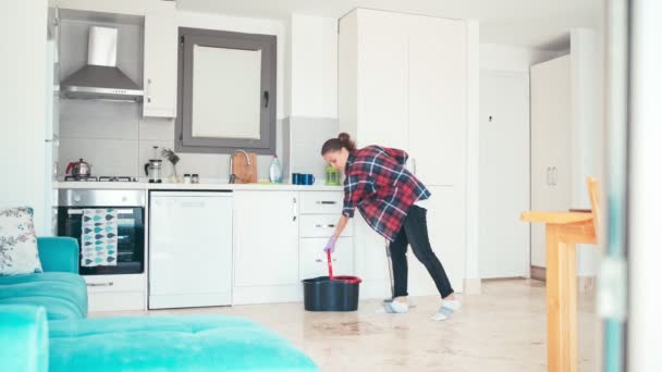 Joven alegre limpiando la cocina fregando el piso haciendo tareas domésticas — Vídeos de Stock