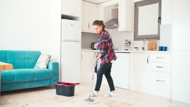 Mutfağı temizleyen, yerleri paspaslayan, ev işi yapan neşeli genç bir kadın. — Stok video