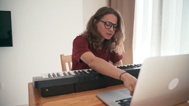 Giovane donna che impara il pianoforte con un corso online utilizzando il suo computer portatile . — Video Stock