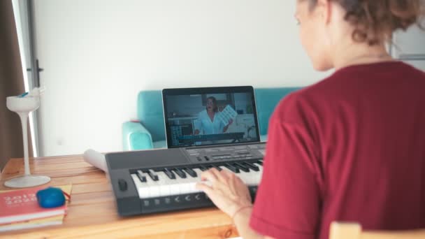 Un joven estudiante viendo lecciones de música en línea y estudiando desde casa . — Vídeo de stock