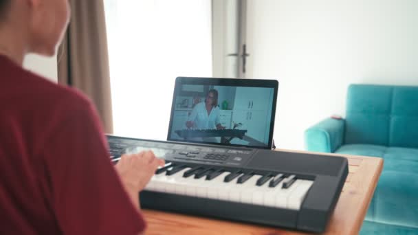 Un jeune étudiant regarde une leçon de musique en ligne et étudie à la maison . — Video