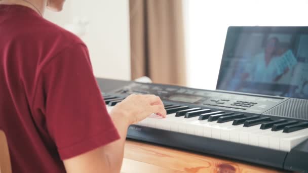 Молодой студент смотрит уроки музыки онлайн и учится на дому . — стоковое видео