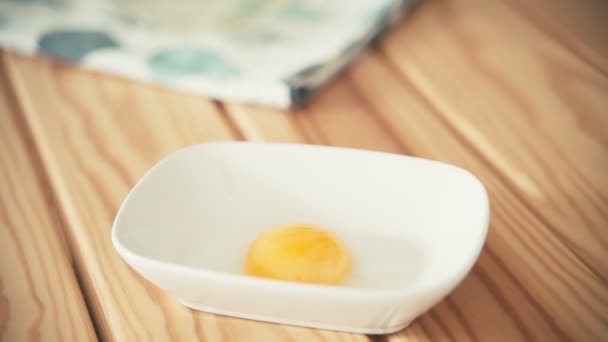 Close up shot of womans hand putting an egg yolk from an eggshell to the bowl. — Stock Video