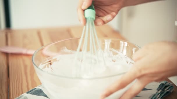 A woman whipping eggs whites with a whisk in a glass bowl — Stock Video