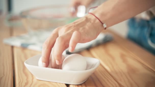 Крупним планом знімок жіночої руки, збираючи куряче яйце з миски — стокове відео