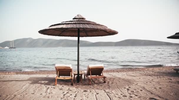 Handgehaltene Aufnahme von leeren Liegestühlen am Strand des Luxushotels. Niemand. — Stockvideo