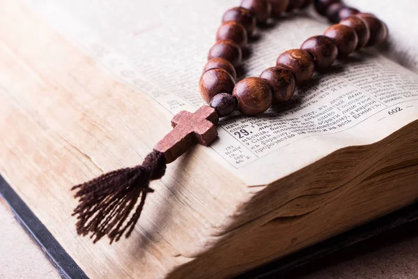 Rosário sobre a Bíblia sobre um fundo de madeira. Livro sagrado . — Fotografia de Stock
