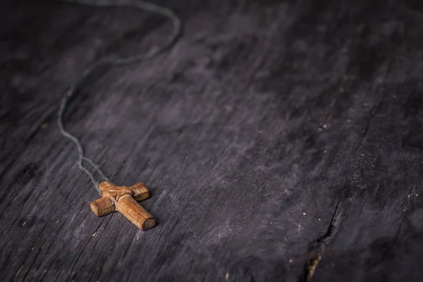 Croce marrone su fondo di legno nero — Foto Stock