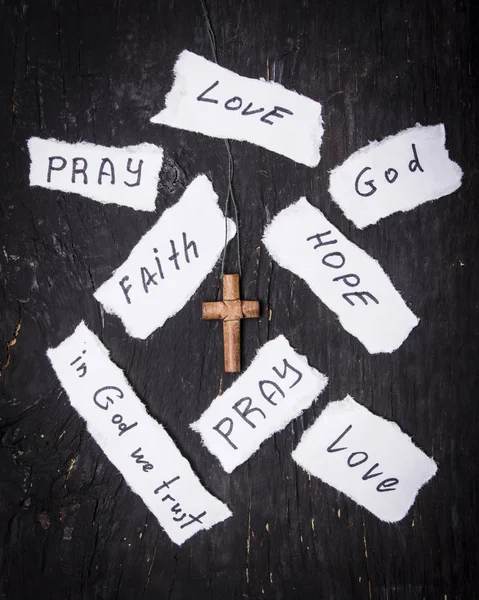 Коричневий хрест на чорному тлі дерев'яні. Напис на білому папері, Віра, надія, любов, Богом, моліться. — стокове фото