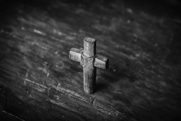 Cross on a black wooden background. Black and white photography