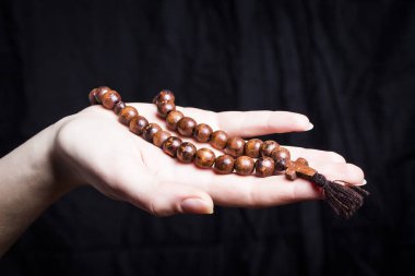 Tespih ve karanlık bir arka plan üzerinde kadın elinde haç 