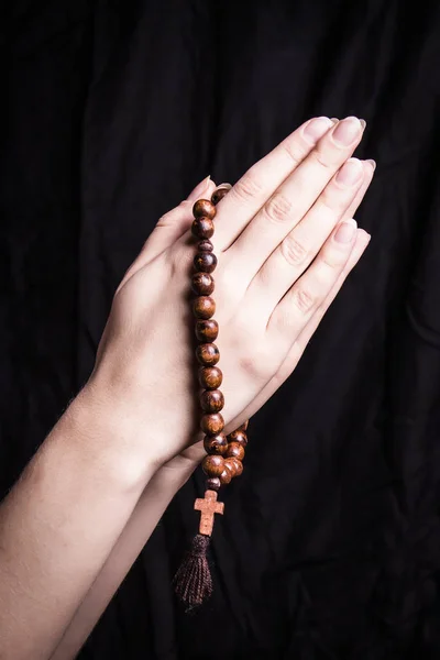 Růženec a kříž v ženských rukou na tmavém pozadí — Stock fotografie