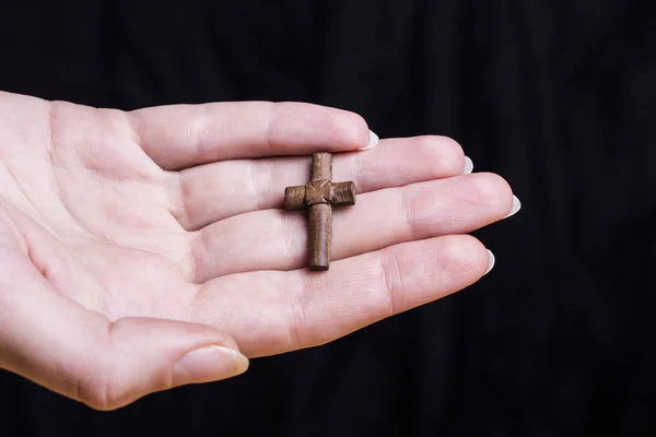 Kreuz in Frauenhand auf dunklem Hintergrund — Stockfoto