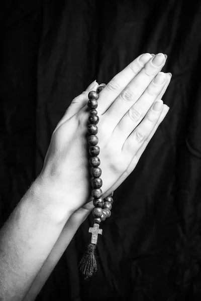 Rosaire et croix dans les mains des femmes sur un fond sombre. Photo noir et blanc . — Photo