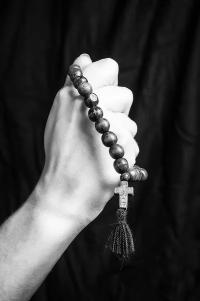Rosaire et croix dans les mains des femmes sur un fond sombre. Photo noir et blanc . — Photo