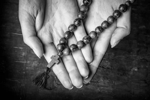 Rosaire et croix dans les mains des femmes sur un fond sombre. Photo noir et blanc . — Photo