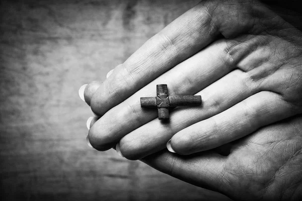 Croix dans les mains féminines sur un fond en bois. Photo noir et blanc . — Photo