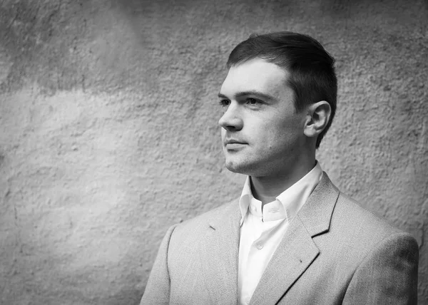 Yakışıklı yiğit adam duvar arka plan üzerinde takım elbiseli. Siyah beyaz fotoğraf