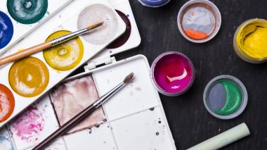 Parlak renkli boya, pastel, boya kalemi, kalem, fırça bir siyah ahşap arka plan üzerinde. Sanatçı için ayarlayın. Eğitim.