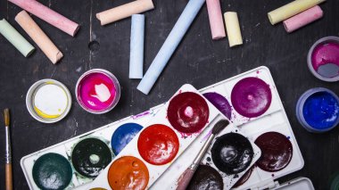 Parlak renkli boya, pastel, boya kalemi, kalem, fırça bir siyah ahşap arka plan üzerinde. Sanatçı için ayarlayın. Eğitim.
