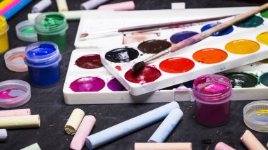 Parlak renkli boya, pastel, boya kalemi, kalem, fırça bir siyah ahşap arka plan üzerinde. Sanatçı için ayarlayın. Eğitim.