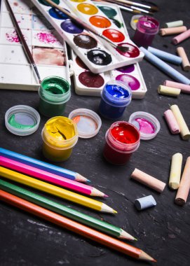 Parlak renkli boya, pastel, boya kalemi, kalem, fırça bir siyah ahşap arka plan üzerinde. Sanatçı için ayarlayın. Eğitim.
