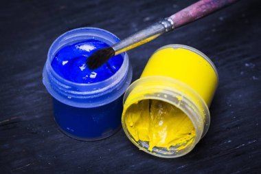 Beyaz Siyah ahşap zemin üzerine fırça ile mavi ve sarı boya. Sanatçı için ayarlayın. Eğitim.