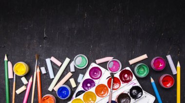 Parlak renkli boya, pastel, boya kalemi, kalem, fırça bir siyah ahşap arka plan üzerinde. Sanatçı için ayarlayın. Eğitim.