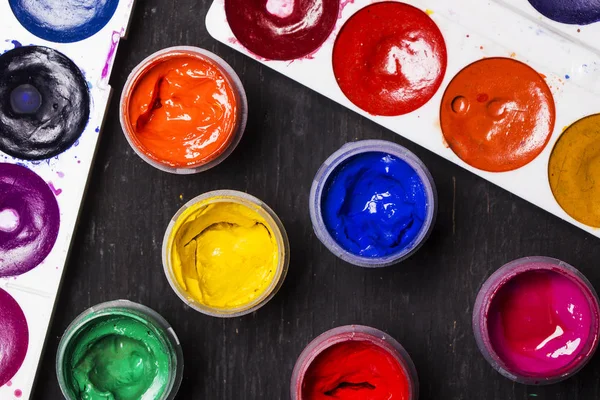 Pintura multicolor brillante sobre fondo de madera negro. para el artista. Educación . — Foto de Stock