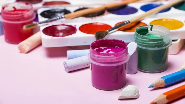 Bright multi-colored paint, pastels, crayons, pencils, brushes on a pink background. Set for the artist. Education. — Stock Photo, Image
