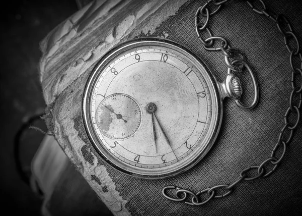 Decaying clock on the background of old shabby wise books. Black and White photograph — Stock Photo, Image