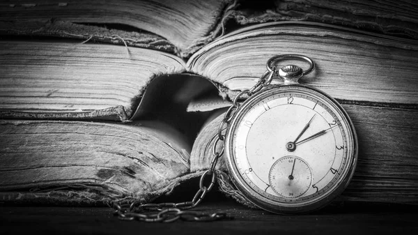 Orologio in decadenza sullo sfondo di vecchi libri squallidi saggi. Fotografia in bianco e nero — Foto Stock