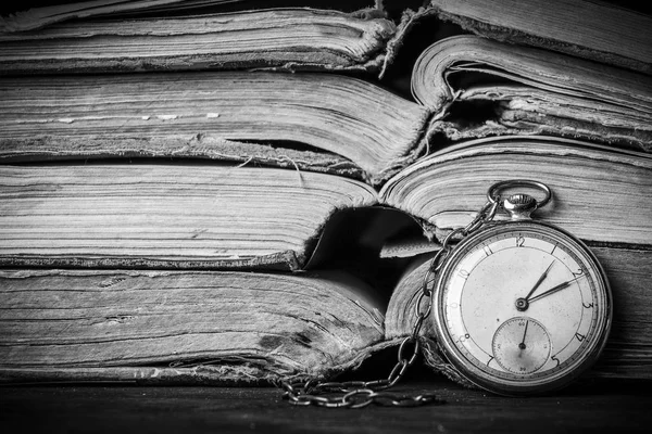 Zerfallende Uhr auf dem Hintergrund alter schäbiger weiser Bücher. Schwarz-Weiß-Fotografie — Stockfoto