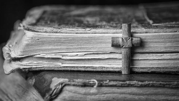 Коричневый крест на Библии на деревянном фоне. Святая книга. Черно-белая фотография — стоковое фото