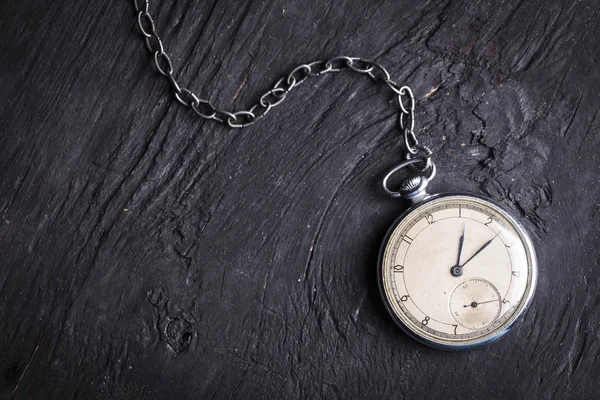 Reloj antiguo sobre una vieja cadena sobre un fondo de madera oscura — Foto de Stock