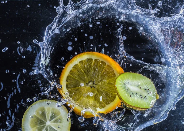 Narenciye su siyah bir arka plan. Sıçramasına Su damlacıkları. Kivi, limon ve mandarin