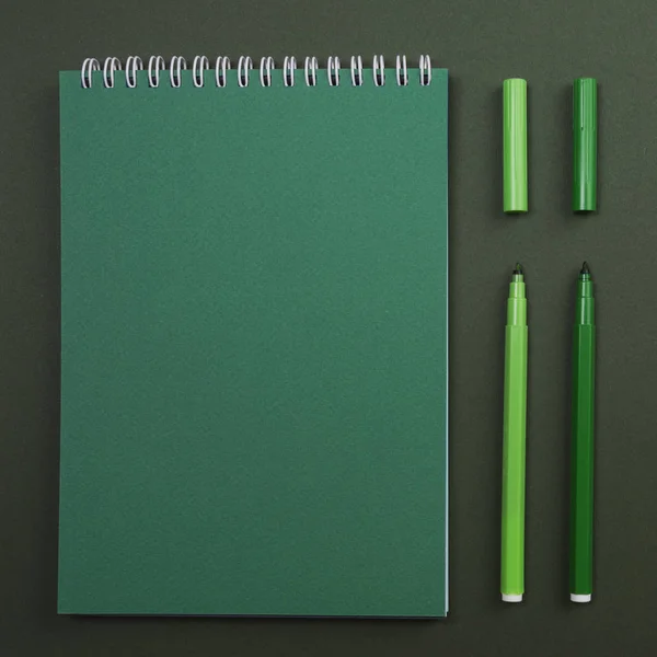 Notebook with markers on green background — Stock Photo, Image
