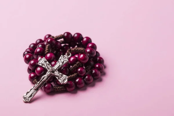 Růženec na růžovém pozadí. Křesťanský kříž. — Stock fotografie