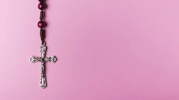 ピンクの背景のロザリオ。キリスト教の十字. — ストック写真