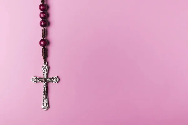 Rosario sobre fondo rosa. Cruz cristiana . Imagen De Stock