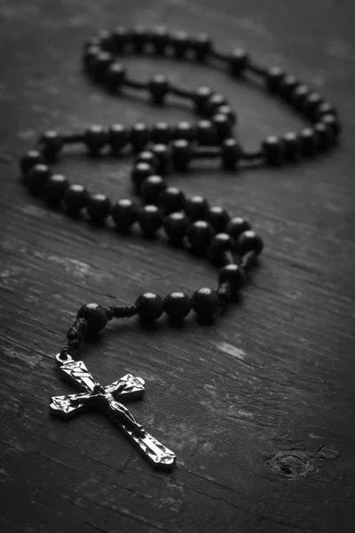 Różaniec z chrześcijańskiej krzyż na tle monofoniczne. Fotografia czarno-białe. — Zdjęcie stockowe