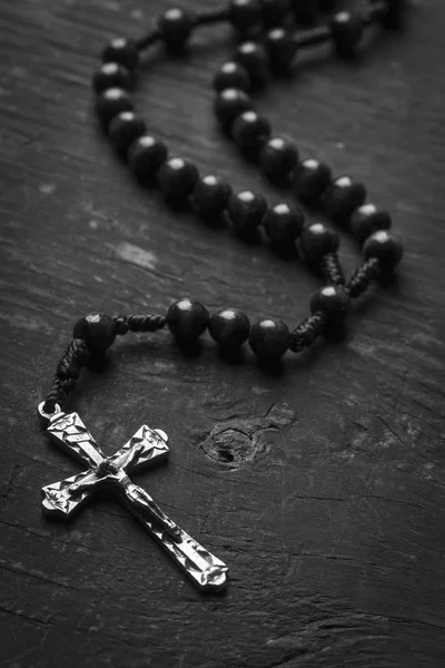 Rosaire avec une croix chrétienne sur fond monophonique. Photographie noir et blanc . — Photo