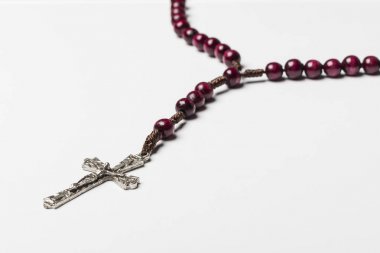 Rosary and a cross on a light gray background.  clipart