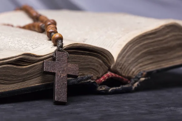 Rosario e croce sulla Bibbia su sfondo ligneo. Libro sacro . — Foto Stock