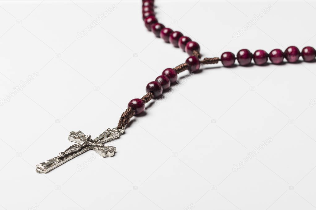 Rosary and a cross on a light gray background. 